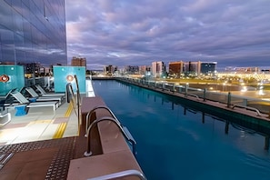 A poolside area with a view of a city skyline at dusk.