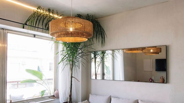 A modern living room with a sofa, a wooden coffee table, a large potted plant, and a hanging light fixture. - Taga suites  (Catania)