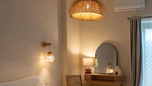 A hotel room with a large bed, a desk with a mirror, and a hanging light fixture. - Taga suites  (Catania)