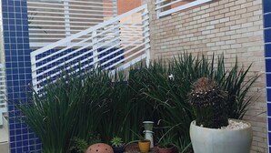 A modern building with a blue-tiled exterior, a white metal fence, and a variety of potted plants.