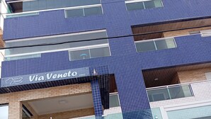 A multi-story building with a blue-tiled facade and a Via Veneto sign.