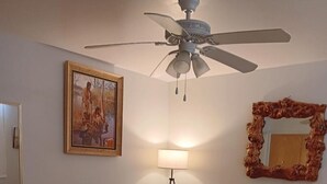 A bedroom with a bed, a ceiling fan, a lamp, a mirror, and a painting on the wall. - Charming 1-Bedroom  Apartment in Great Neighborhood (Great Falls)