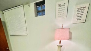 A small, cozy room with a brown leather bench, a glass coffee table, a pink lamp, and a beige sofa. - Charming 1-Bedroom  Apartment in Great Neighborhood (Great Falls)