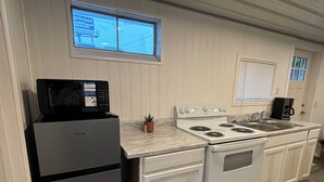 A compact kitchen with a refrigerator, stove, microwave, and sink.