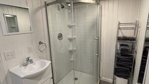 A bathroom with a glass-enclosed shower, a sink, and a towel rack.