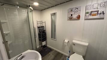 A bathroom with a shower, sink, toilet, and a towel rack.