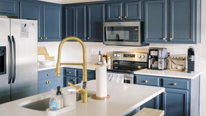 Una cucina moderna con mobili azzurri, elettrodomestici in acciaio inossidabile e un piano di lavoro bianco.