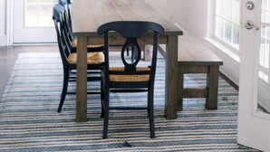 Zona pranzo con tavolo e sedie in legno, lampadario a sospensione e un quadro appeso al muro.