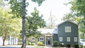 A two-story house with a front porch, a stone foundation, and a well-maintained lawn. - Spacious, Private, Beautiful Lot in Holiday Shores (Dadeville)