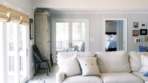 A living room with a beige sofa, a black chair, and a glass door leading to an outdoor area. - Spacious, Private, Beautiful Lot in Holiday Shores (Dadeville)