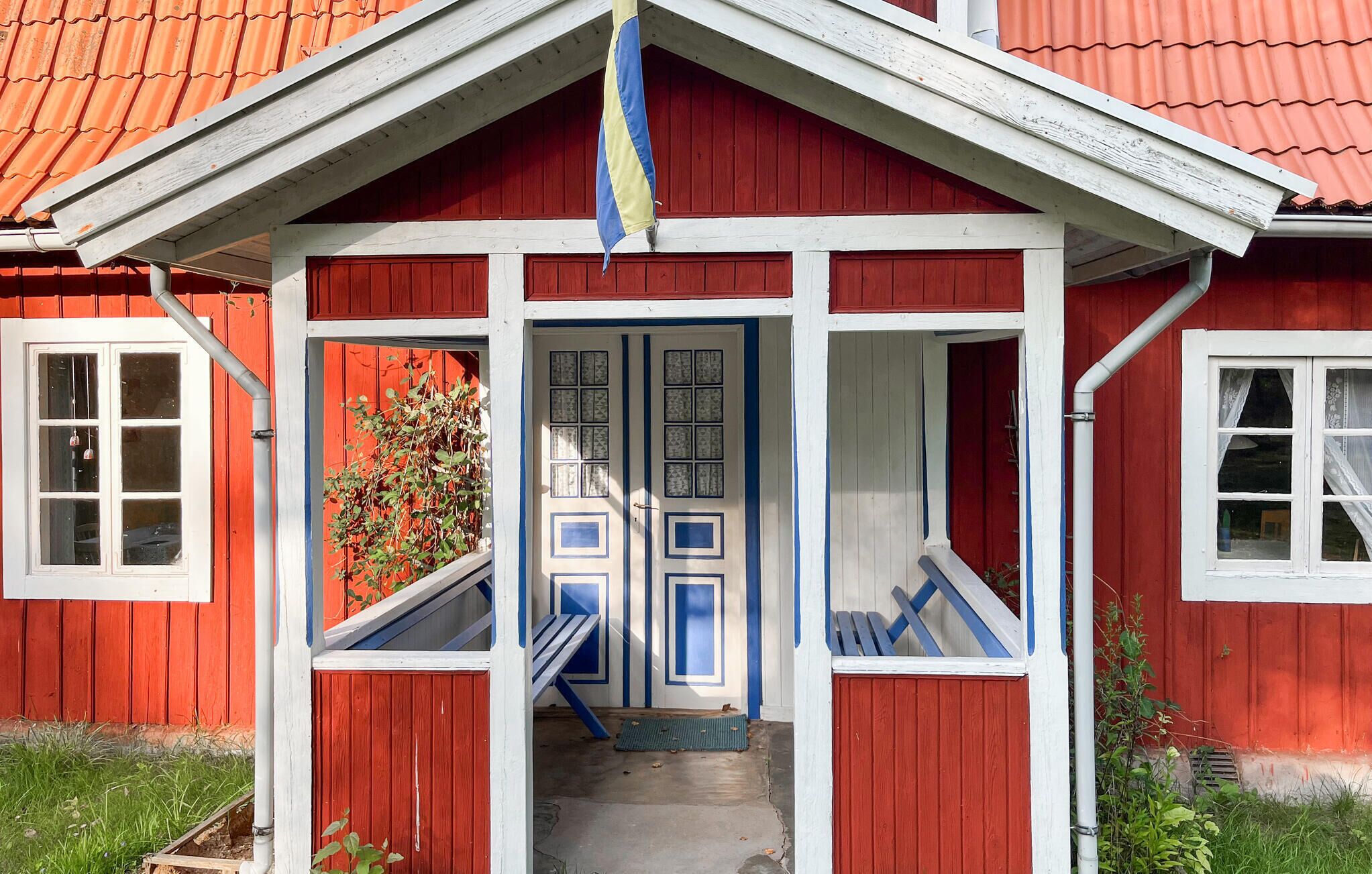 A red wooden house with a white porch and blue accents.