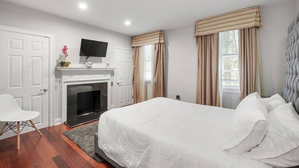 Un dormitorio con cama, televisor, chimenea y cortinas.