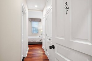 A narrow hallway with a bed in the background, a door with a number, and a window with blinds. - Spacious 6BR En Suite Rittenhouse Home (Philadelphia)