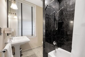 A bathroom with a white sink, a mirror, and a shower area with black marble tiles. - Spacious 6BR En Suite Rittenhouse Home! Sleeps 14! (Philadelphia)