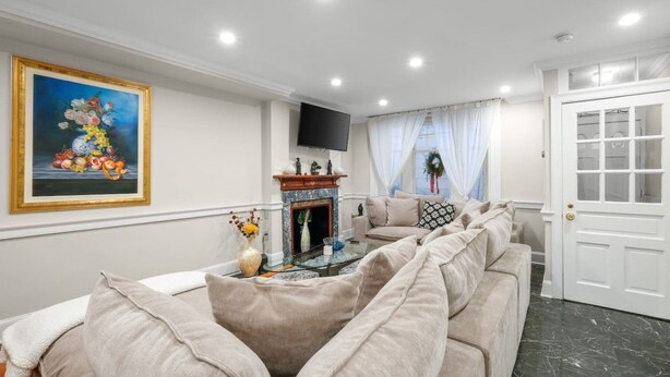 Ein Wohnzimmer mit einer Sofagarnitur, einem Kamin, einem Fernseher und einer Tür.