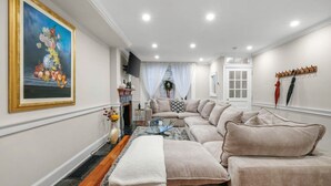 Una sala de estar con un sofá, una chimenea, un televisor y un cuadro en la pared.