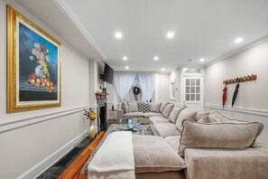 A living room with a sofa, a fireplace, a television, and a painting on the wall. - Spacious 6BR En Suite Rittenhouse Home (Philadelphia)