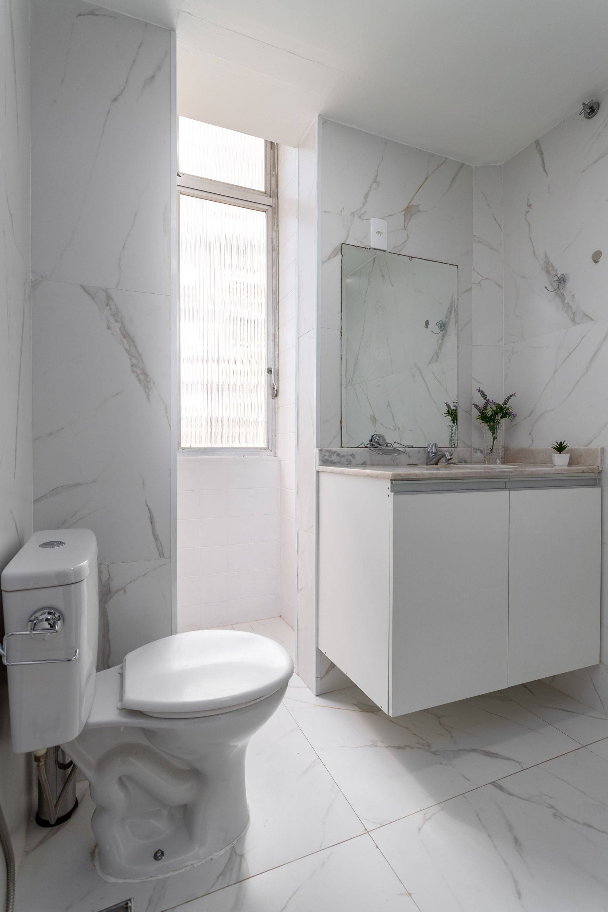 A modern bathroom with a toilet, sink, and mirror.