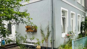 Ein Wohngebäude mit einem Kiesweg, der zu einer hölzernen Bank führt.