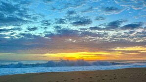 A beach with footprints leading to the water, waves crashing, and a sunset with clouds in the sky. - Jungle House, 100m From the Beach, With Private Pool (Bocas del Toro)