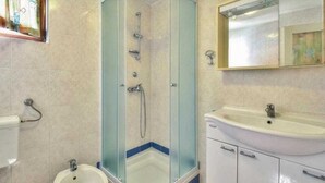 Ein Badezimmer mit Duschkabine, Waschbecken auf Säule und Toilette.