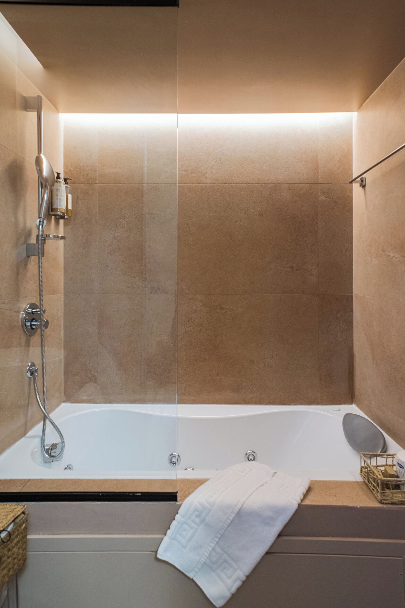 Un baño moderno con una bañera independiente, un box de ducha de cristal y un mueble de tocador de madera con una toalla.
