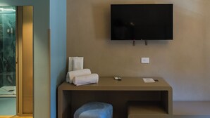 Una habitación moderna con televisión de pantalla plana montada en la pared, un banco y un pequeño reposapiés.