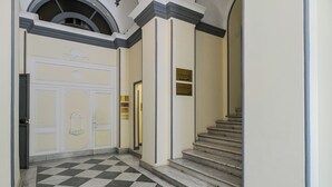 Un pasillo con piso a cuadros, una escalera y una puerta con una placa.