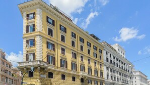 Un edificio de varios pisos con fachada amarilla y adornos blancos, con múltiples ventanas y balcones.