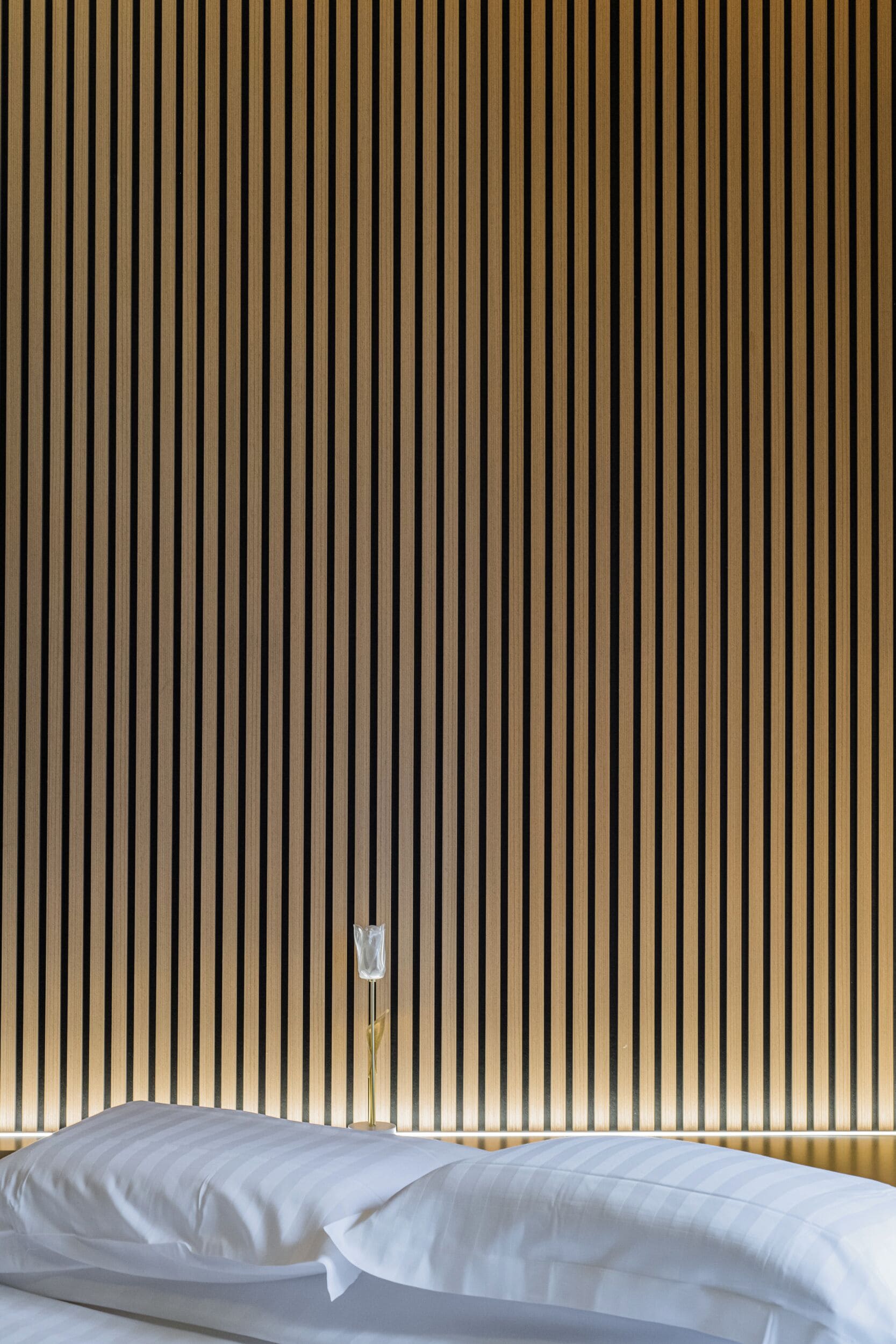 Een kamer met een bed tegen een wand met verticale houten latten.