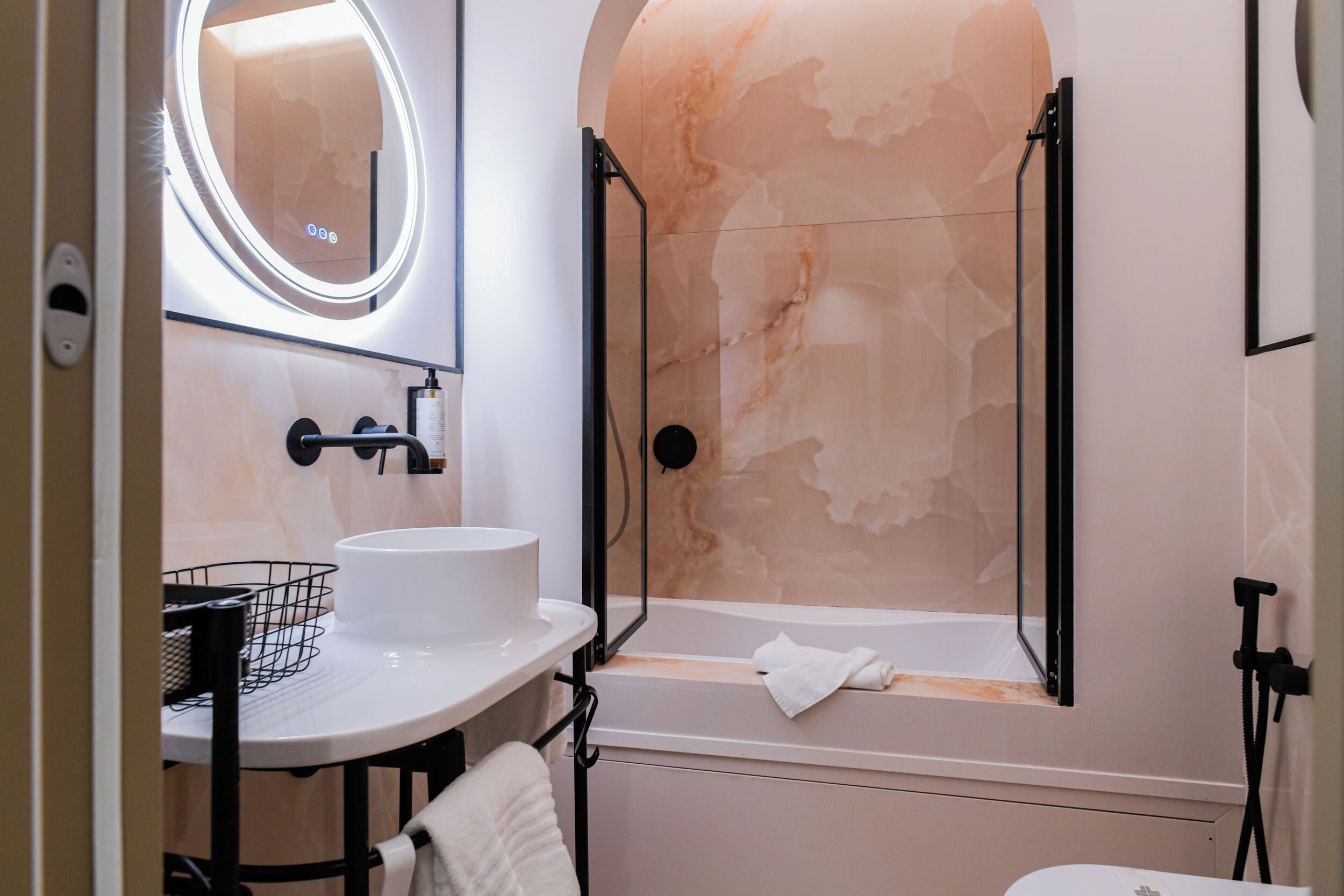 A modern bathroom with a round mirror, a sink, and a bathtub.