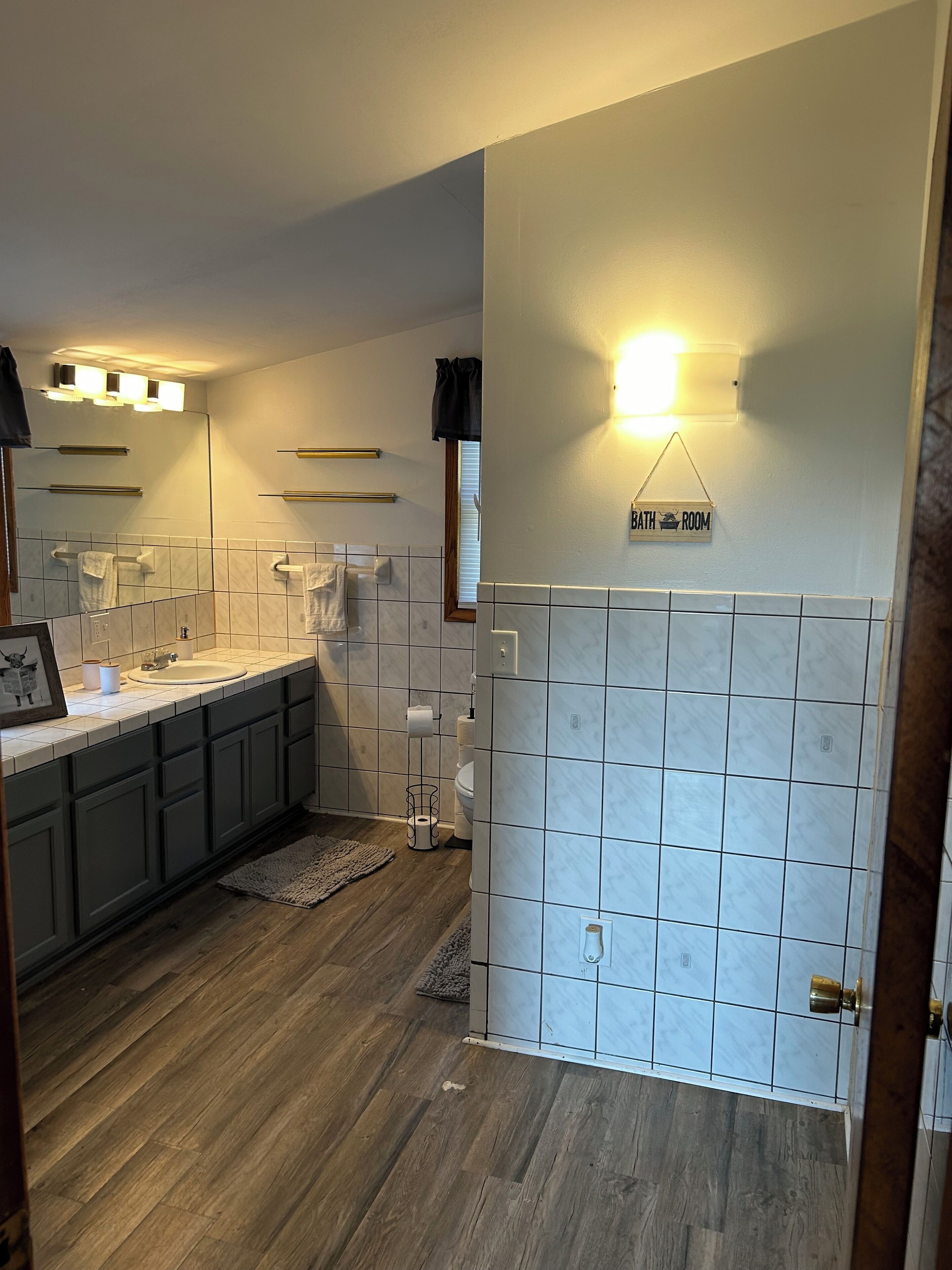 A bathroom with a sink, toilet, and towel rack, featuring a sign that reads "BATHROOM."