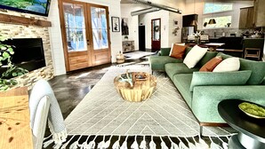 A spacious living room with a green sofa, a fireplace, and a television.