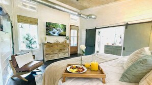 A bedroom with a bed, bedside table, dresser, and a large window.