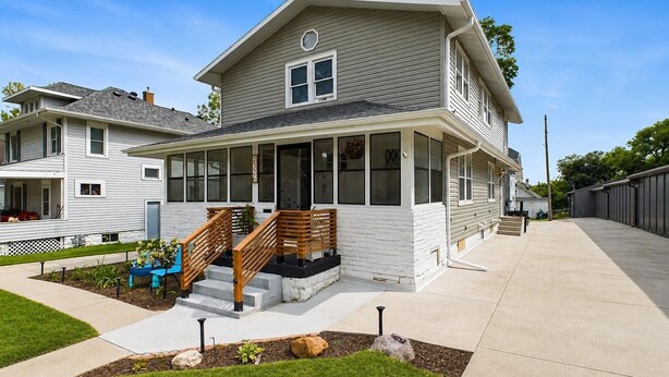 A two-story house with a covered porch, a staircase, and a well-maintained lawn. - Best Value 2BR Midtown Stay - Clean + Central (Omaha)