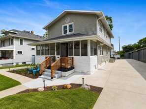 A two-story house with a covered porch, a staircase, and a well-maintained lawn.