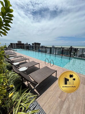 A rooftop pool with lounge chairs and a view of the city skyline. - Melhores Flats - Perfeição perto do mar (João Pessoa)