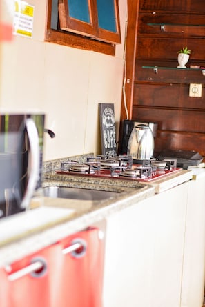 A kitchen with a gas stove, a coffee maker, and a cabinet. - Suli Pousada (Florianópolis)