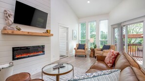A modern living room with a fireplace, comfortable seating, and large windows.