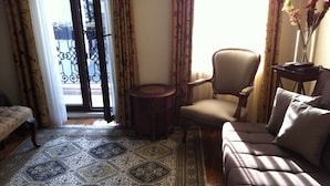 A living room with a patterned rug, a sofa, a chair, and a small table. - Dila Suites (Istanbul)