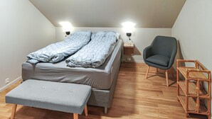 A small, modern bedroom with a bed, a chair, a wooden floor, and two wall-mounted lights. - 3 bedroom stunning home in Avaldsnes (Avaldsnes)