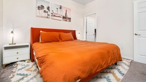 A bedroom with a bed, a nightstand, a door, and wall art. - Beautiful Home Walk to UF  Newly built (Gainesville)