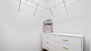 A laundry room with a white cabinet, a laundry basket, and a metal drying rack. - Beautiful Home Walk to UF  Newly built (Gainesville)