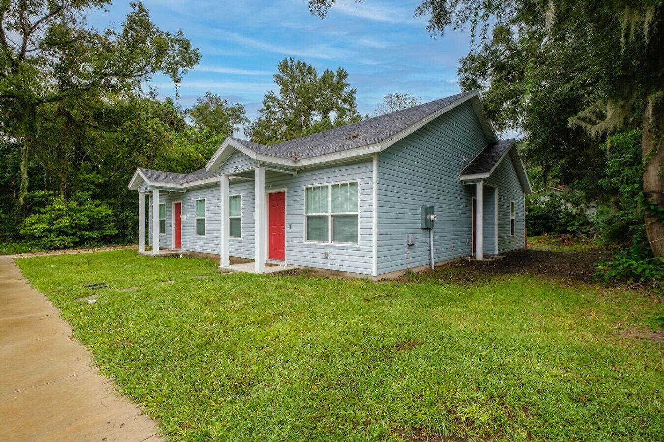A two-story house with a red door and a covered porch.