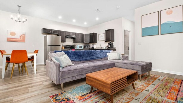 A modern living room with a grey sectional sofa, a wooden coffee table, and a colorful rug. - Beautiful Home - Walk to UF - Newly built (Gainesville)