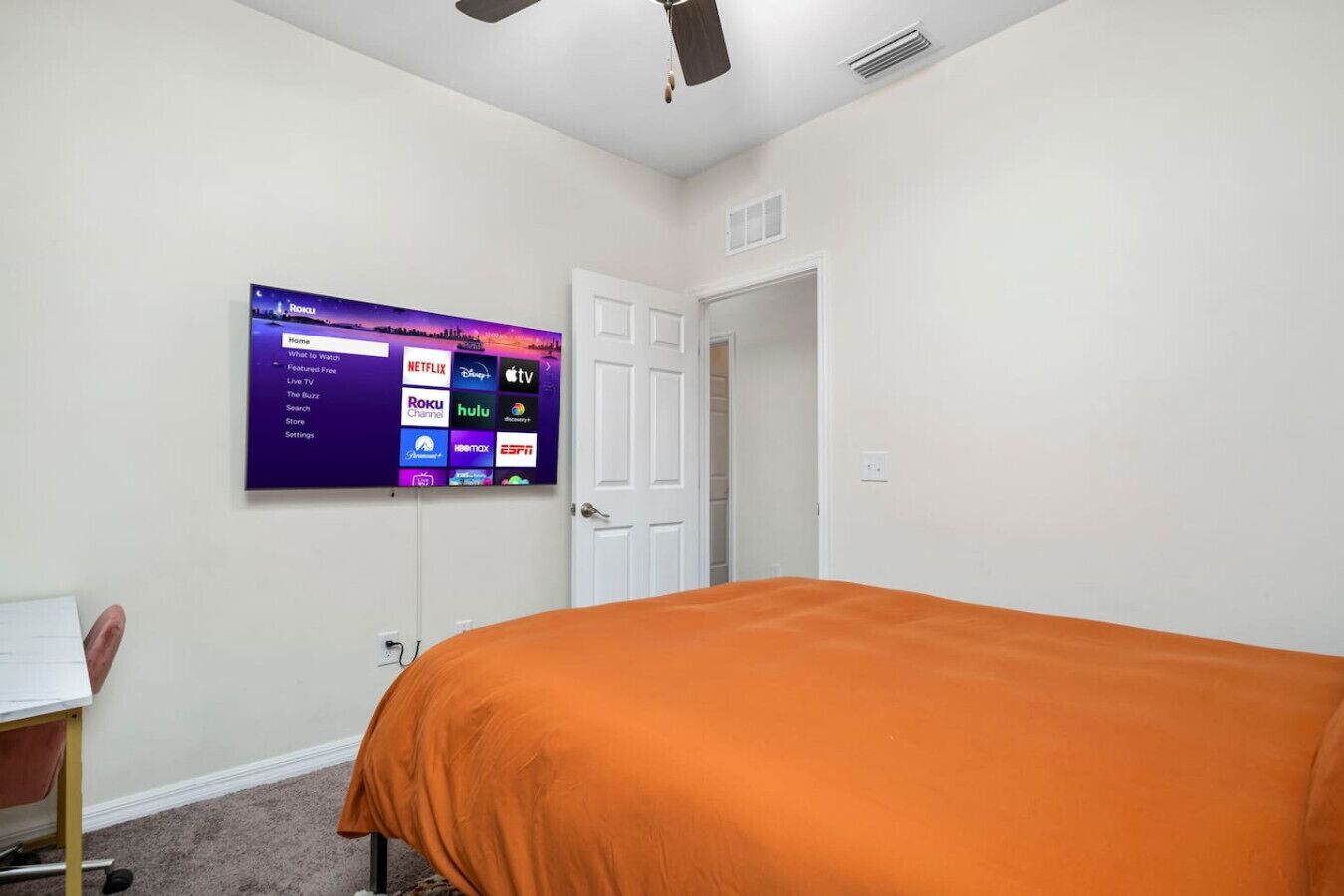 Une chambre à coucher avec un lit, un téléviseur diffusant des services de streaming et une porte donnant sur une autre pièce.