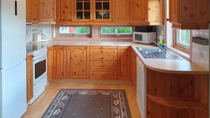A kitchen with wooden cabinets, a microwave, a sink, and a stove.