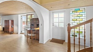 Una habitación amplia con suelo de madera, un escritorio con una silla, un armario y una escalera con barandilla de madera.