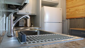 Una cucina con lavello in acciaio inox, piano cottura integrato e frigorifero bianco.