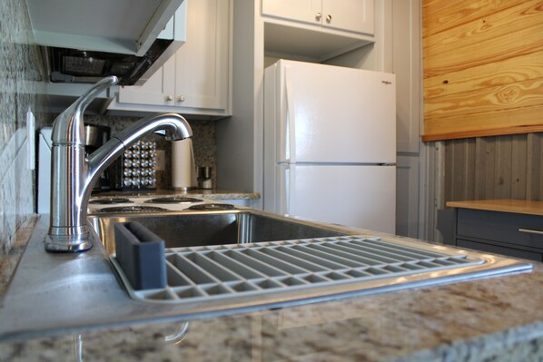 A kitchen with a stainless steel sink, a built-in stove, and a white refrigerator. - 7Js Waco Western Club - Privacy, View, Pool & Hot Tub (Riesel)